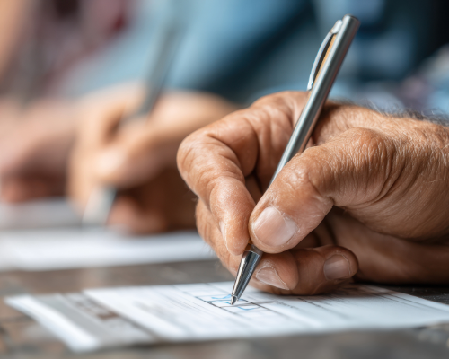 Image of a line of hands writing information into casting ballots